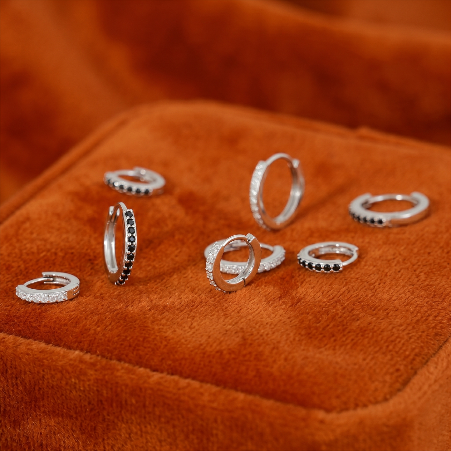 Mix of huggie hoop earrings: silver-tone with clear and dark stone rows