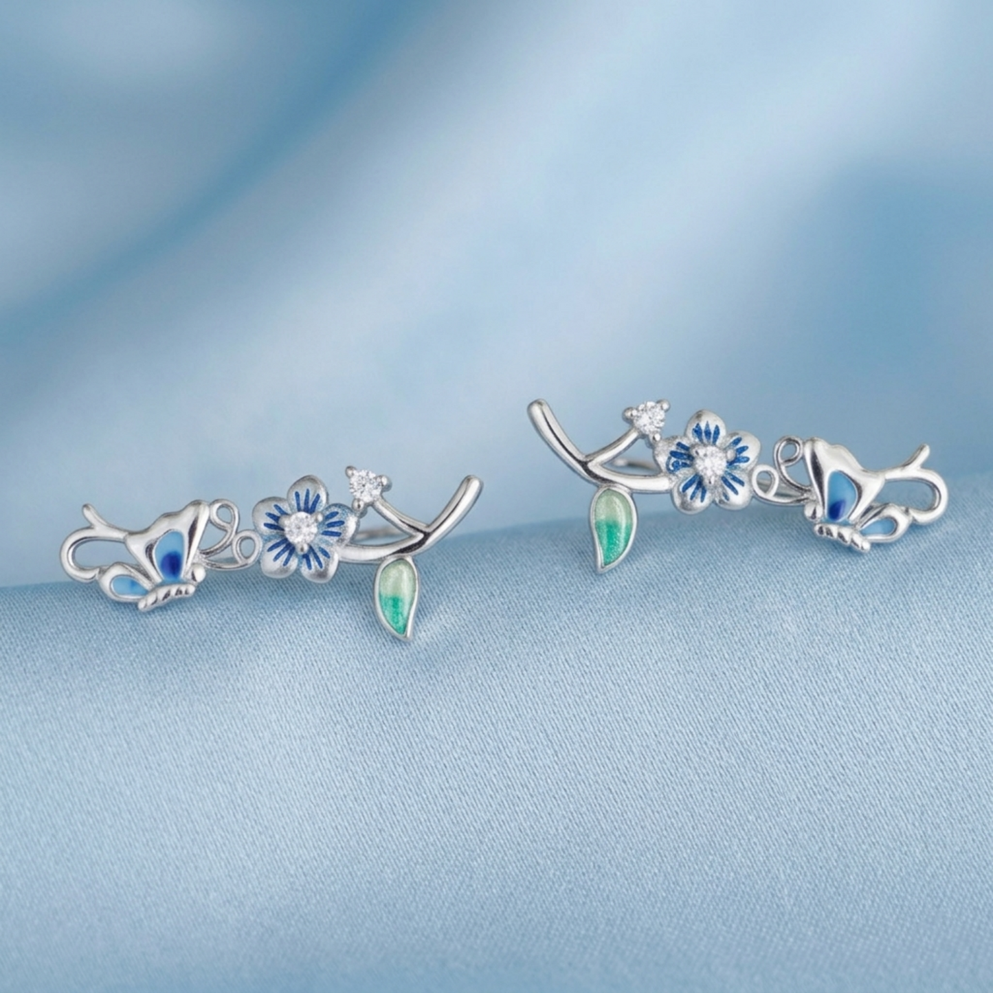 Butterfly climber earrings set with blue enamel butterflies, crystal blooms, and enamel leaves.