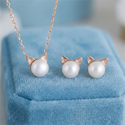 Cat pearl necklace pendant with matching cat-face stud earrings on a display cushion