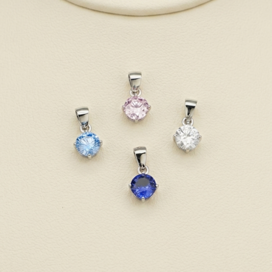 Group of round CZ solitaire pendants on short silver-toned chains in pink, blue, and clear.