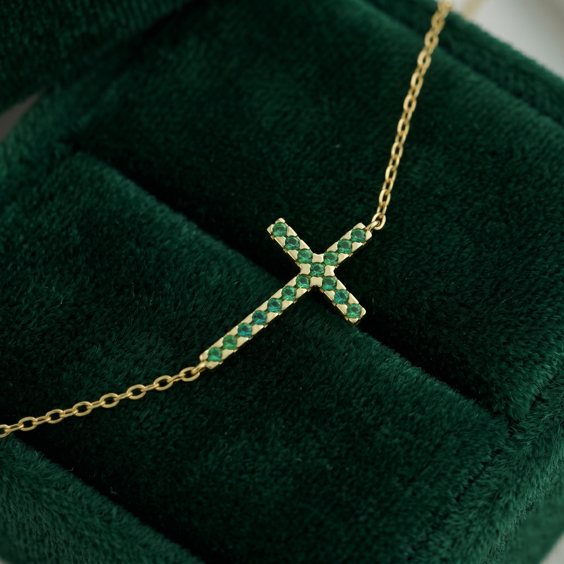 Sideways green CZ cross pendant with small emerald-cut stones on gold chain