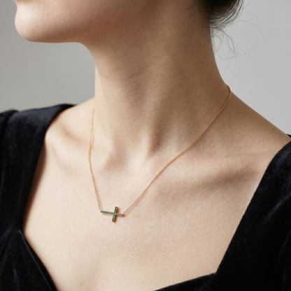 Sideways green CZ cross necklace on gold-tone chain from profile angle