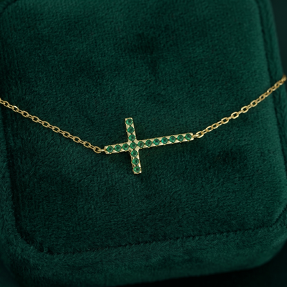 Close-up: sideways green CZ cross pendant on gold-tone chain