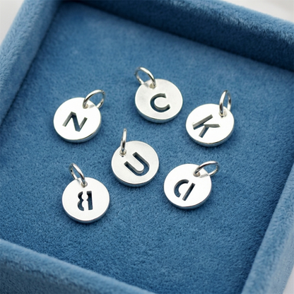 Silver hollow alphabet disc charms with circular discs and letter cutouts on loops