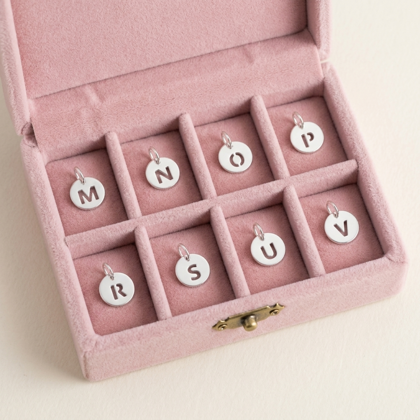 Silver hollow alphabet disc charm set with letter discs in a pink jewelry box