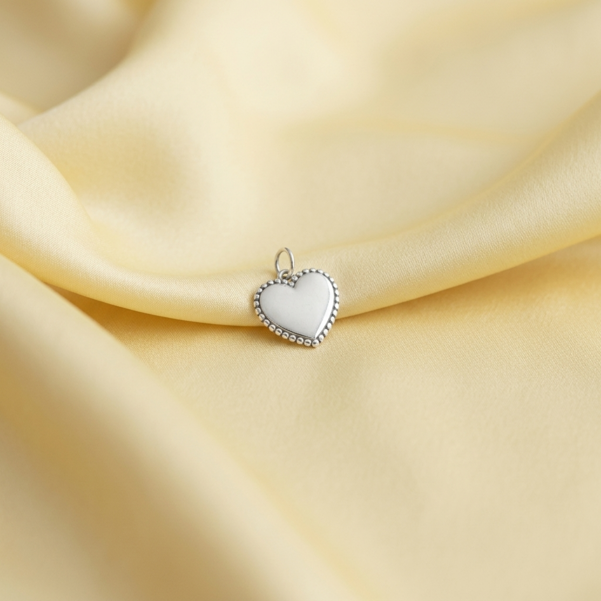 Small silver heart charm pendant with beaded border and top loop