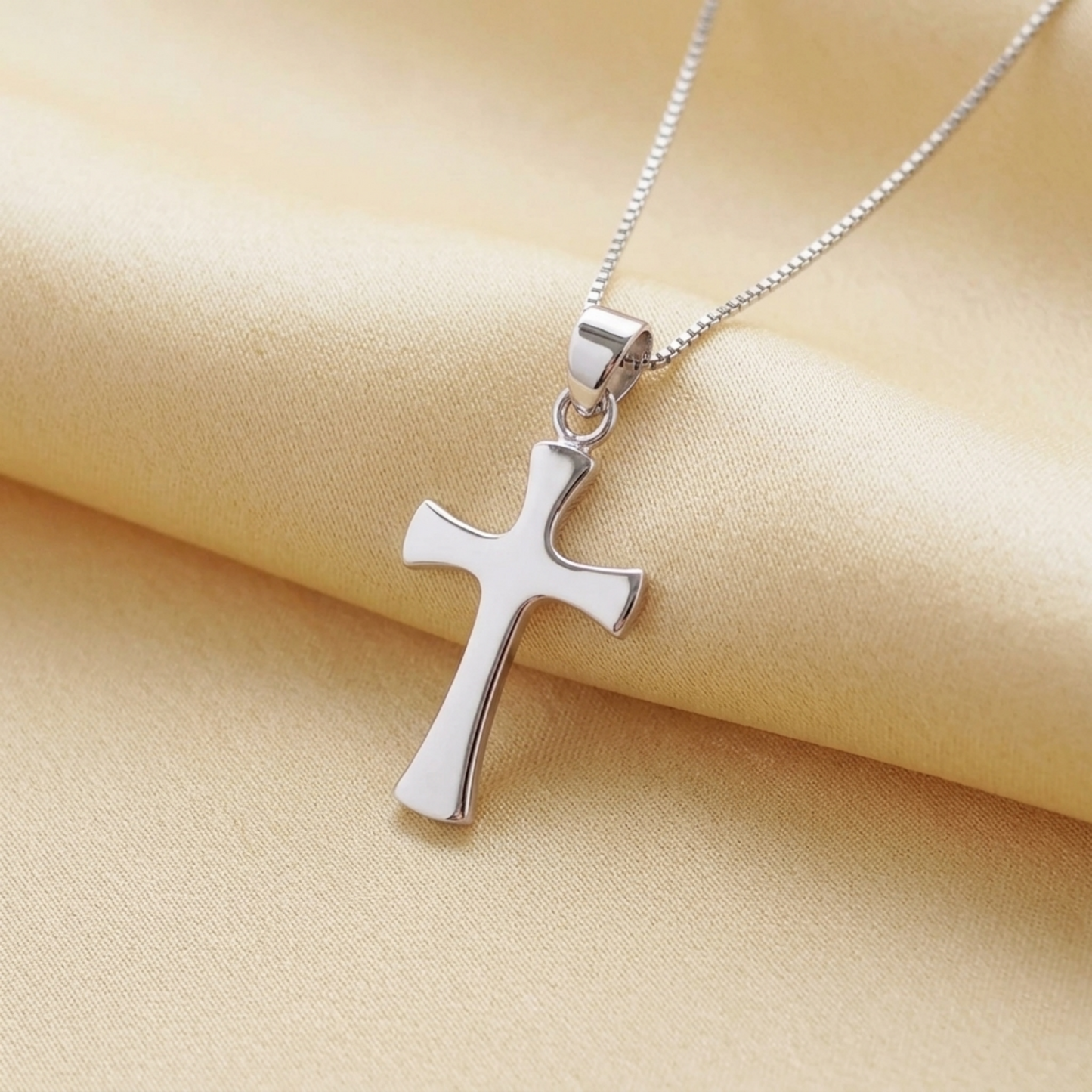 Polished flared cross pendant on fine chain, close view of top loop and cross