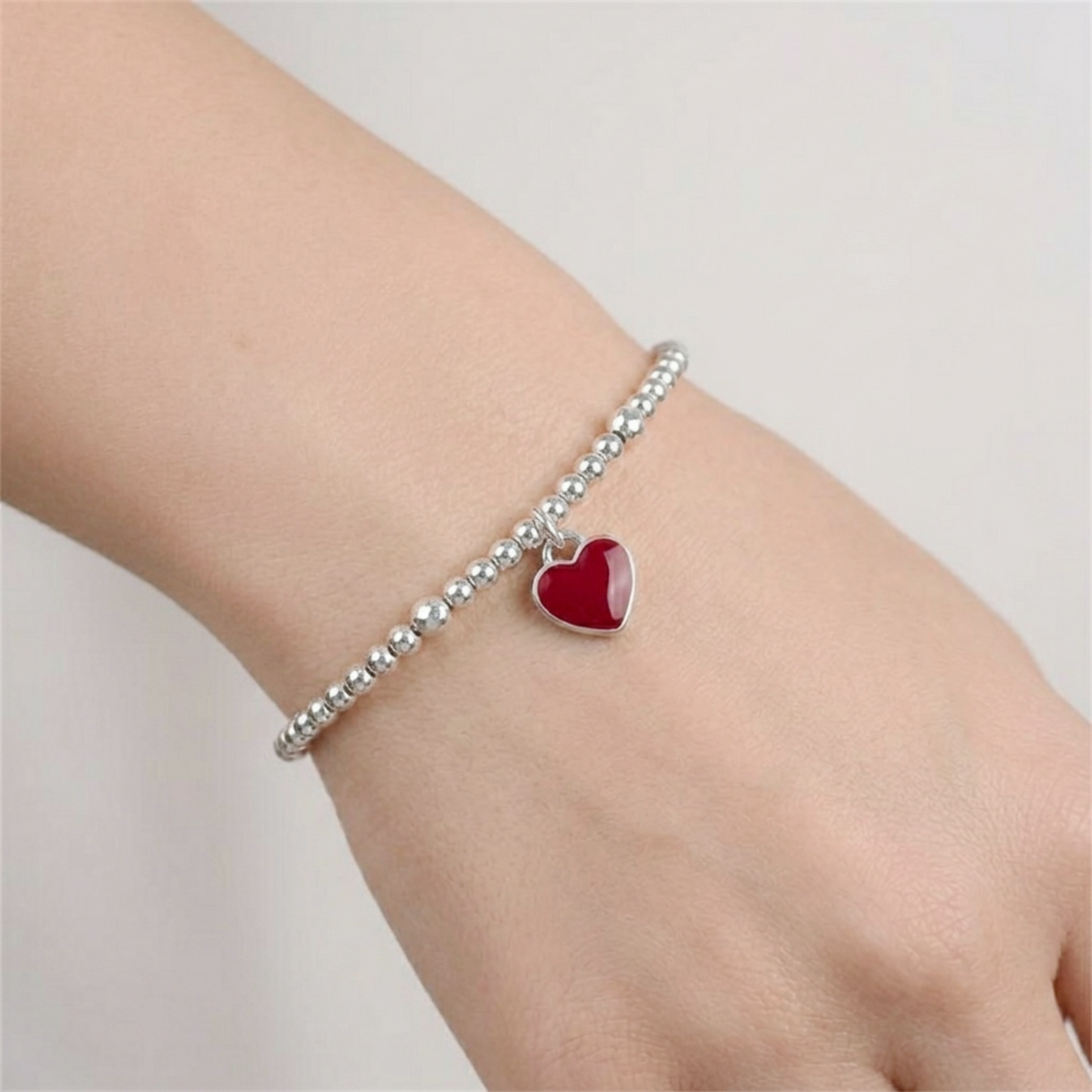 Red heart charm on silver bead bracelet, heart-shaped glossy enamel pendant