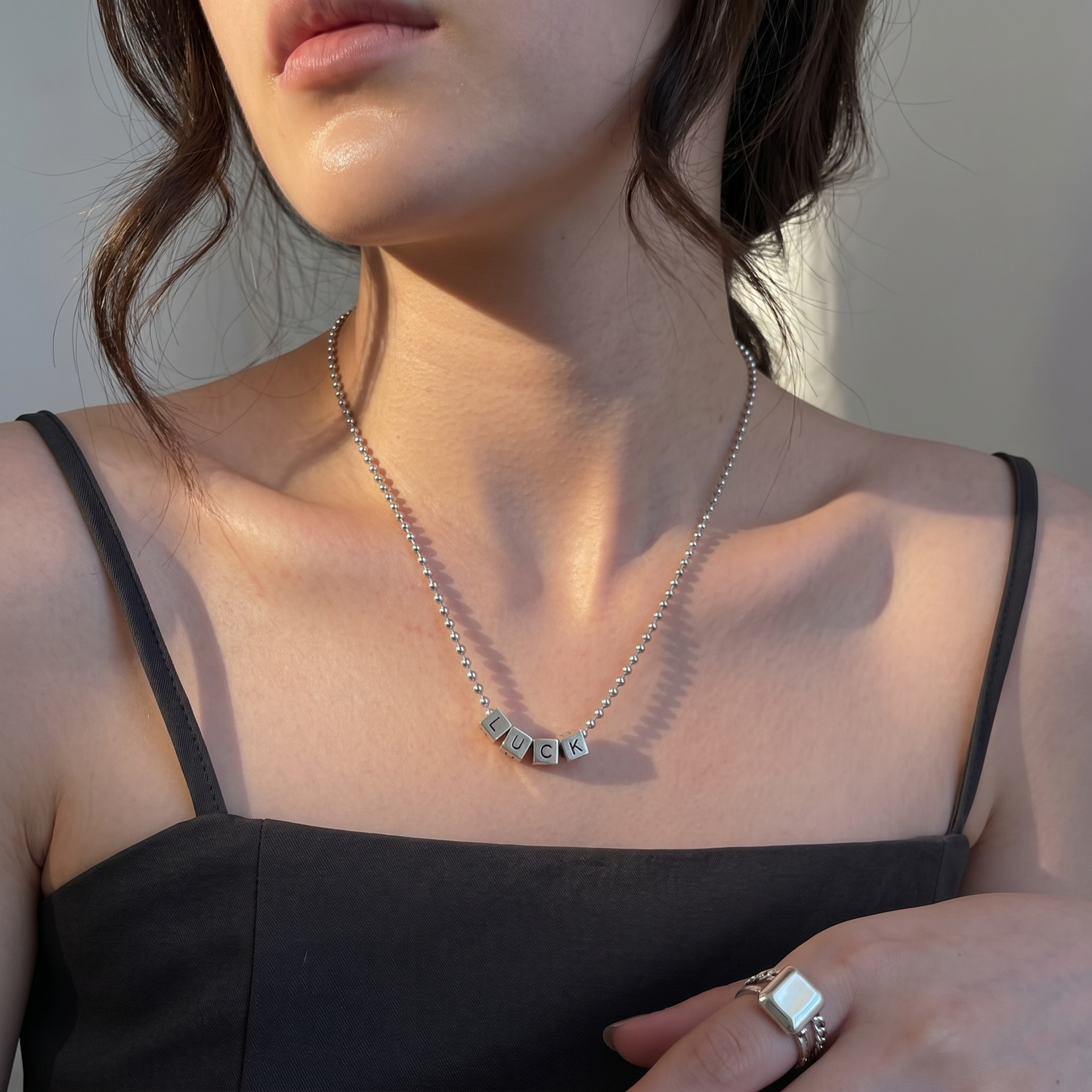 Alphabet cube bead necklace with engraved letters U, C, K across the chain