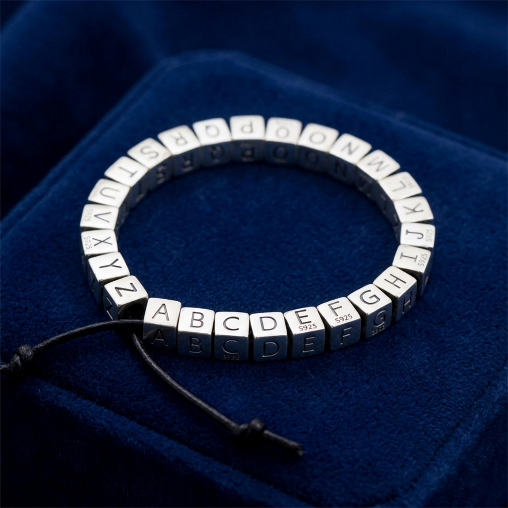 Alphabet cube bead bracelet with stacked letter cubes A–V on a dark cord