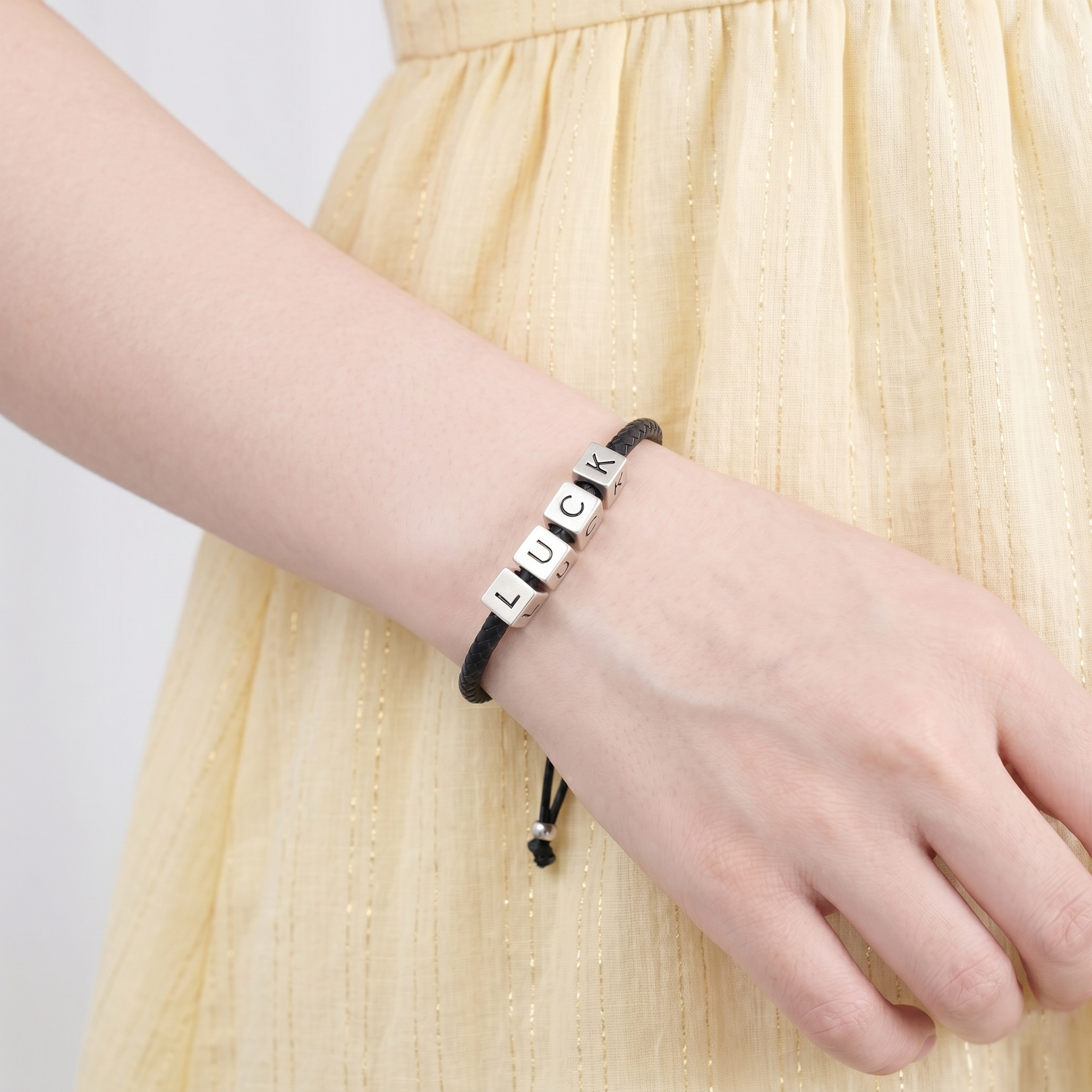 Alphabet cube bead bracelet on wrist with visible letters U, C, K, D, E