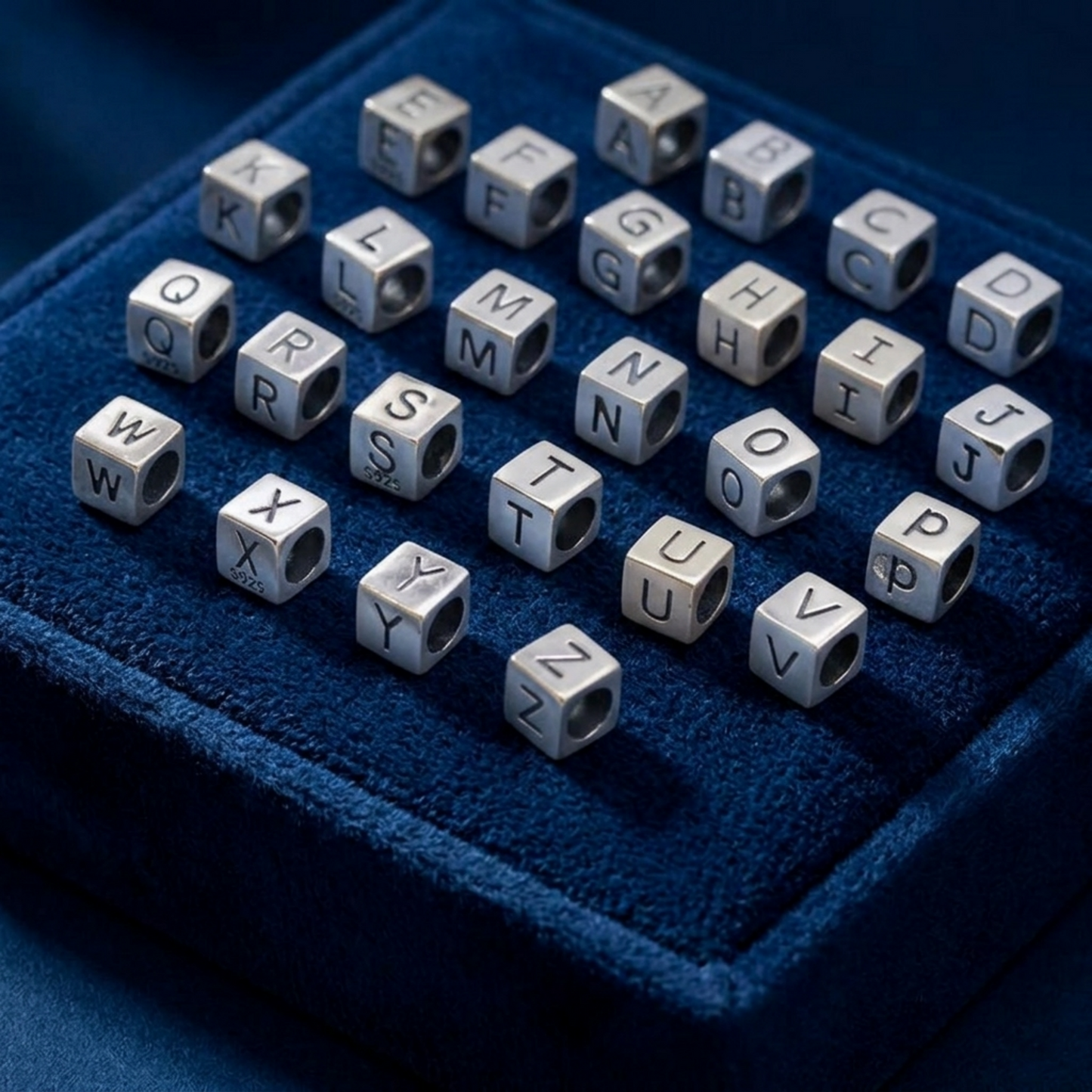 Alphabet cube beads on blue velvet, metal cubes with engraved letters A–Z