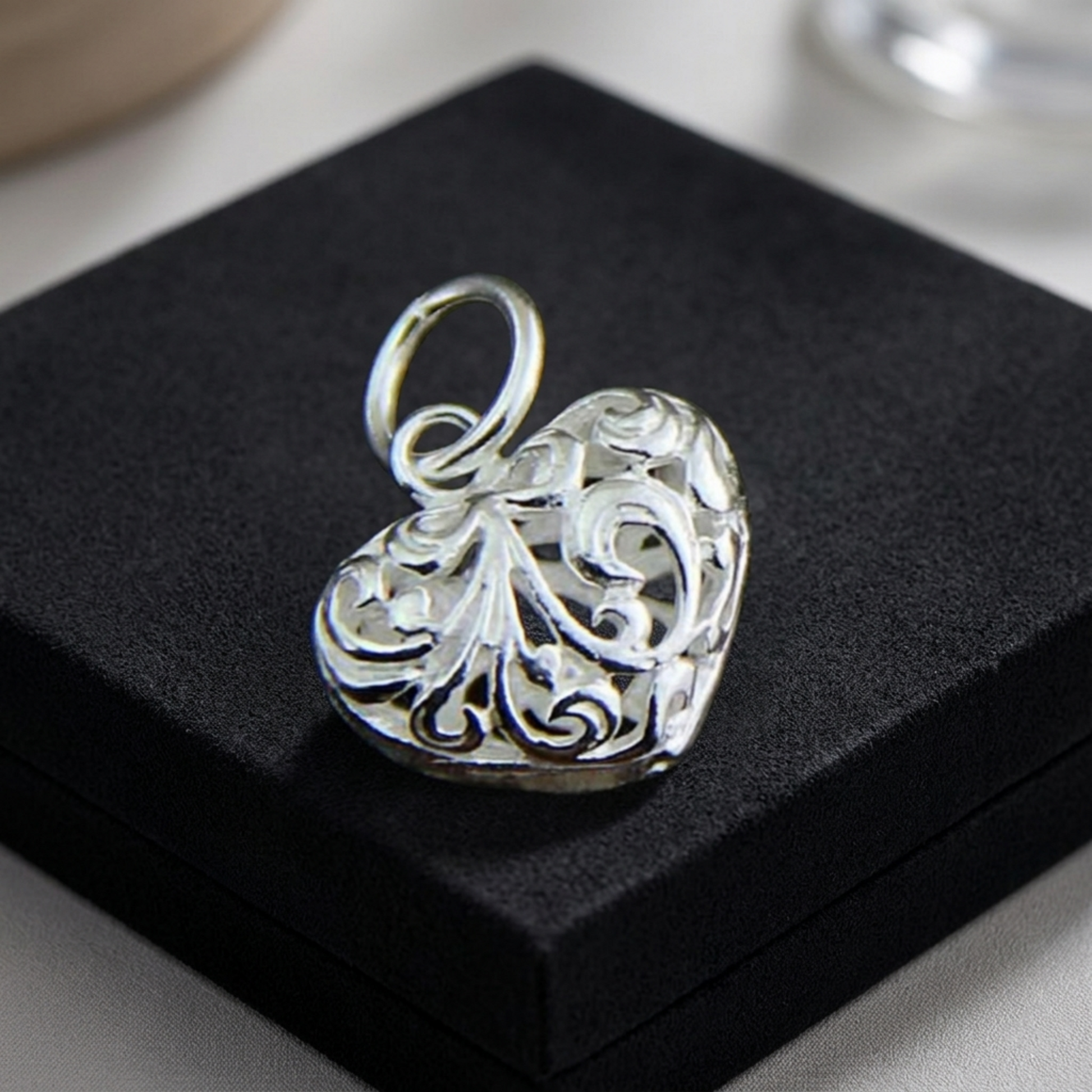 Angled view of silver-tone filigree floral heart pendant