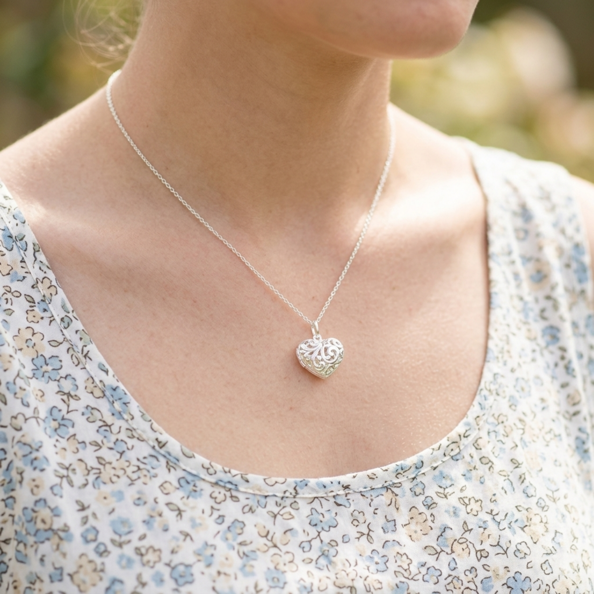 Silver-tone heart pendant necklace on model, with floral-pattern top