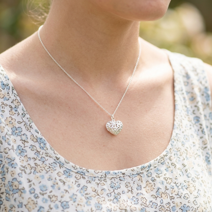 Silver-tone heart pendant necklace on model, with floral-pattern top