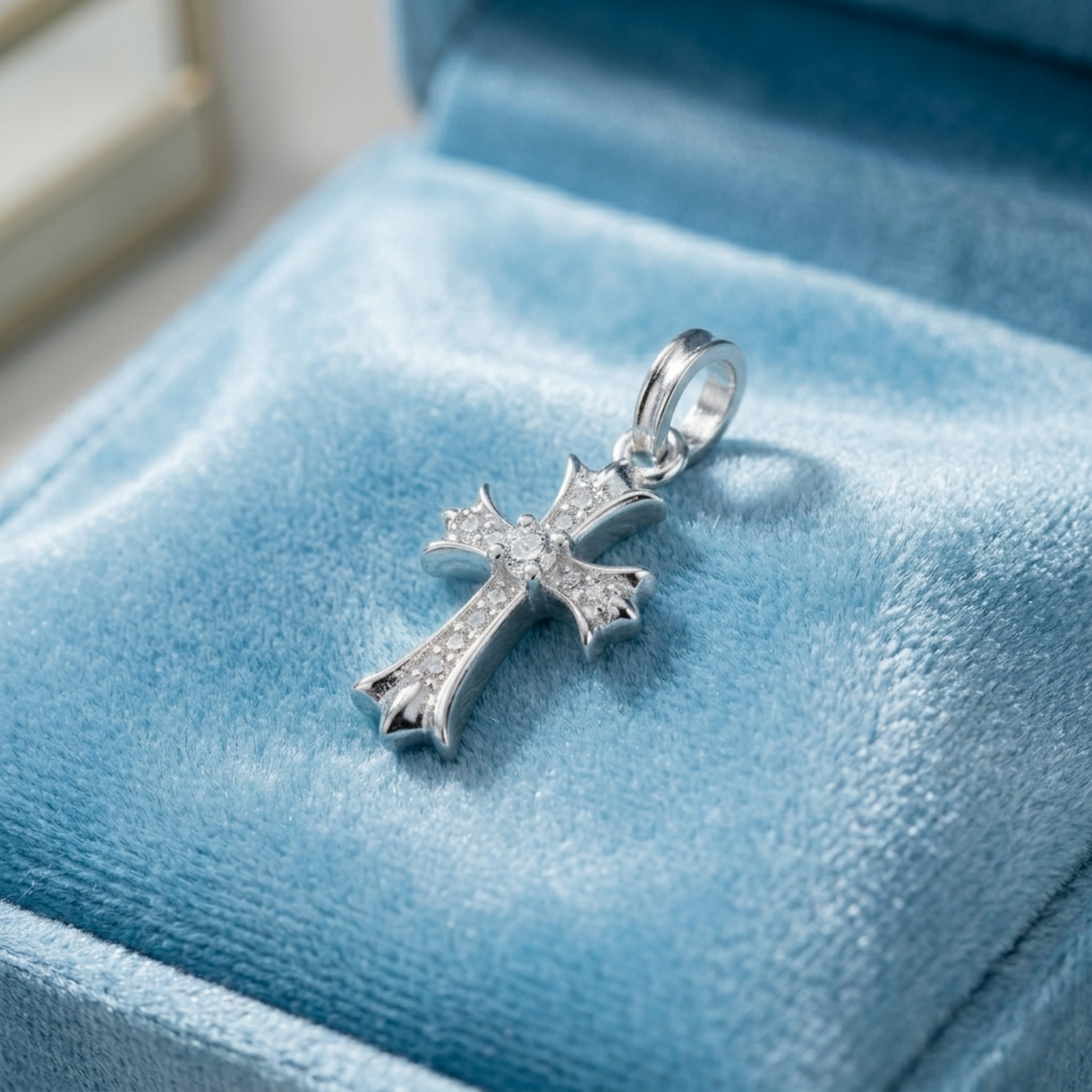 Silver CZ cross pendant on a blue display with round-cut crystal details