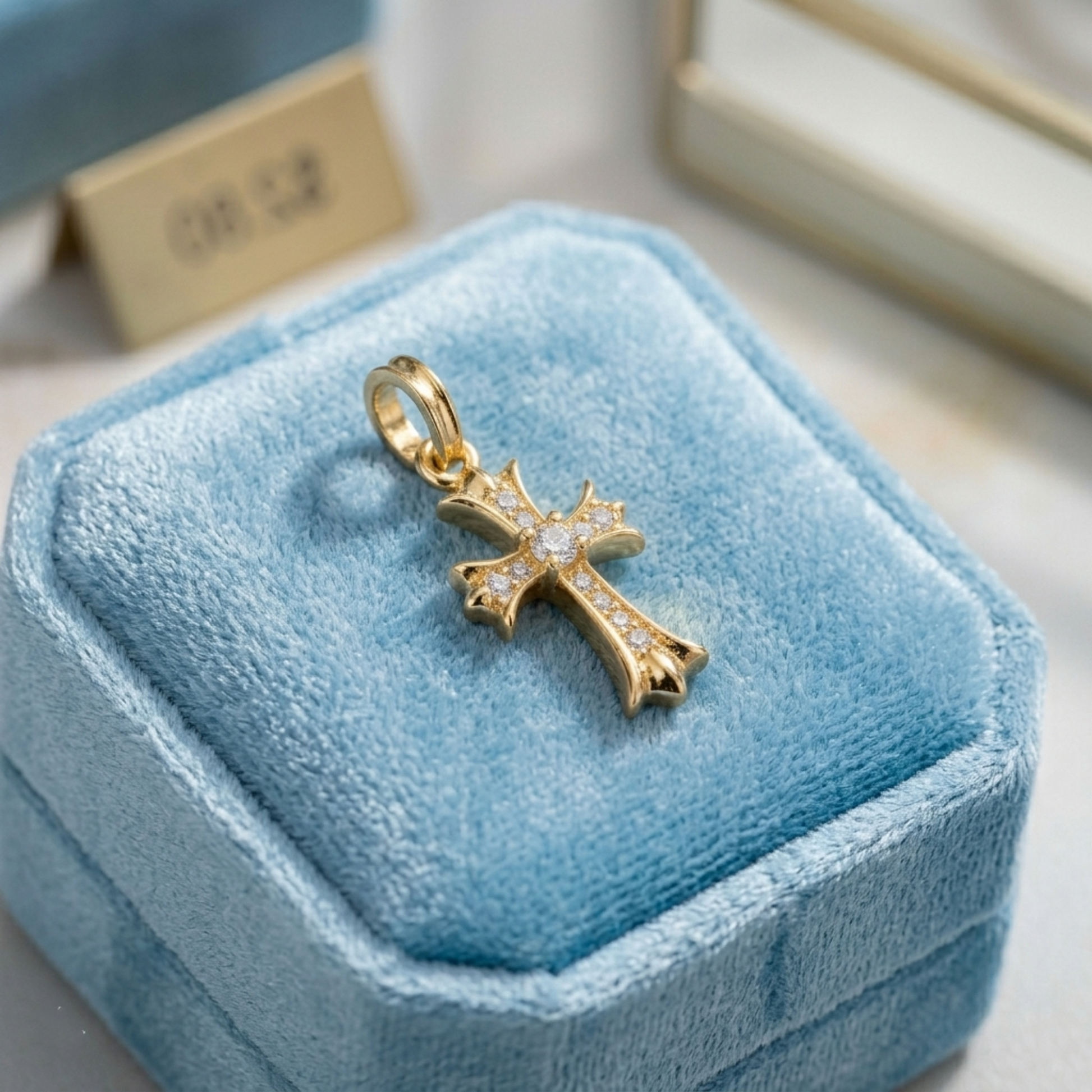 Gold CZ cross pendant on a blue display with round-cut crystal accents