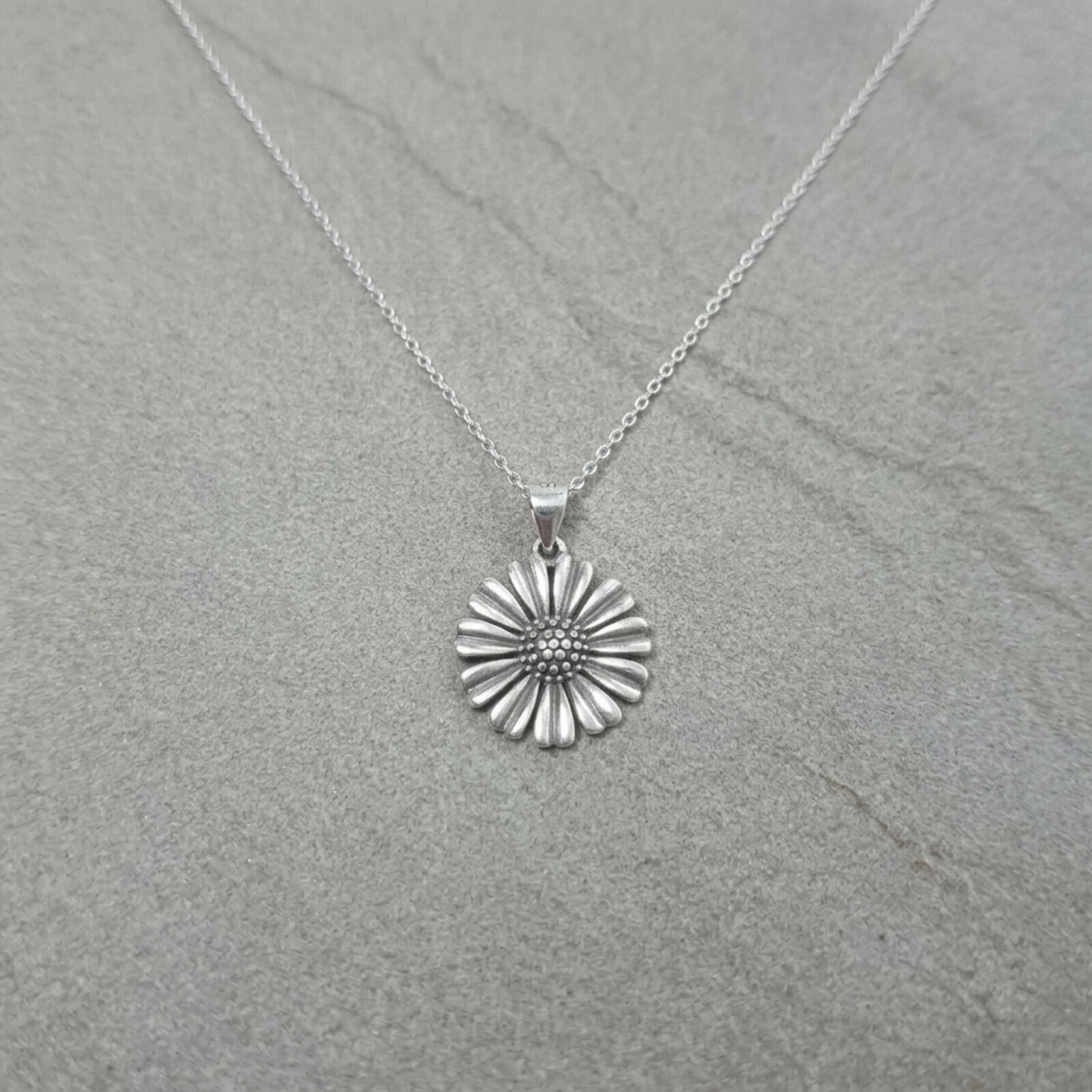 Small daisy pendant on necklace chain, ridged petals and dotted center