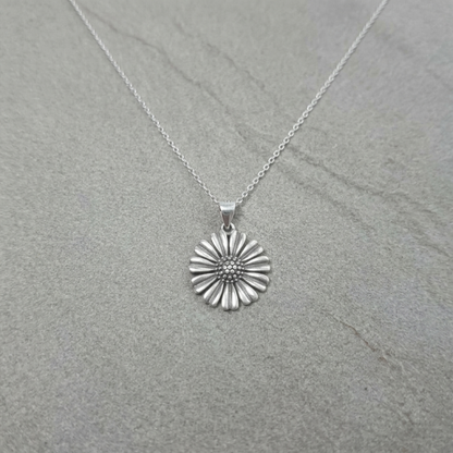 Small daisy pendant on necklace chain, ridged petals and dotted center