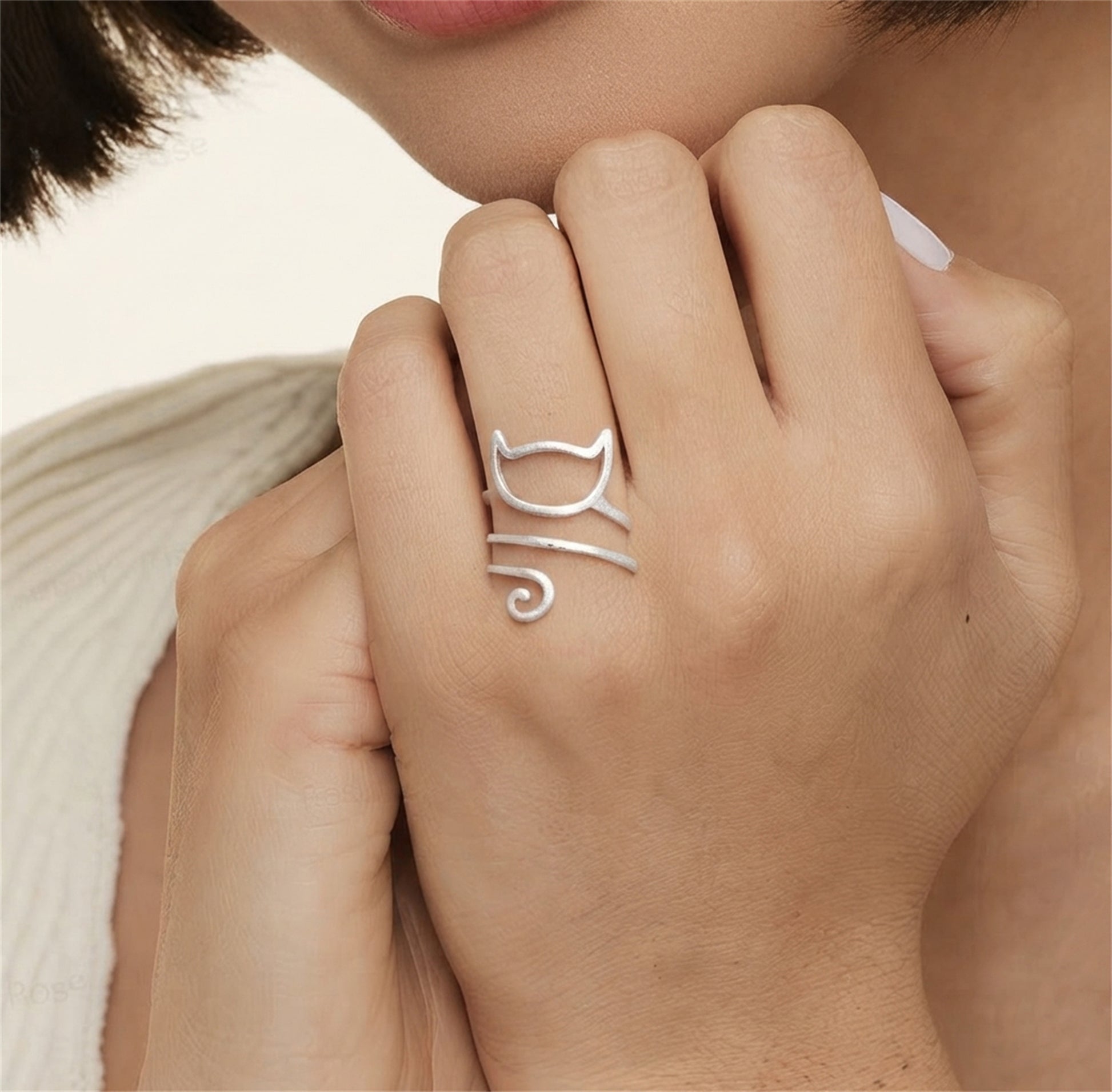 Kitten wraparound ring on finger, silver cat-face motif with curly tail detail.