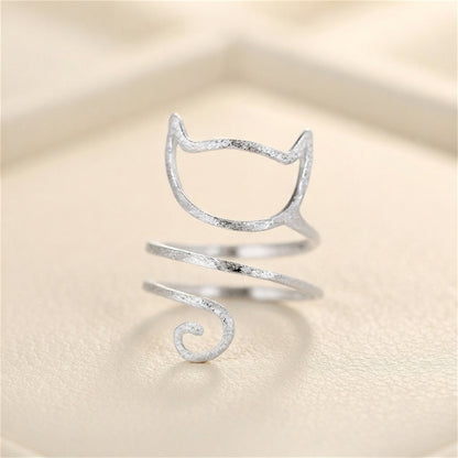 Silver-tone kitten wraparound ring on fabric, cat-face design with spiral tail.