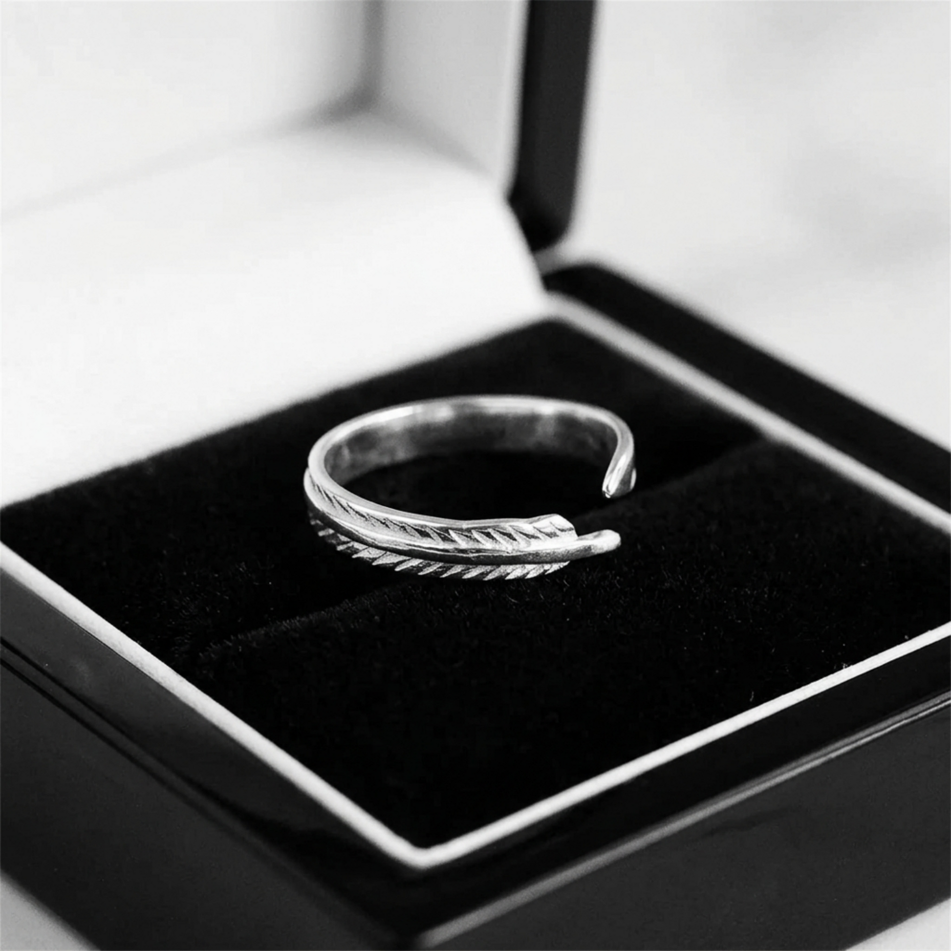 Feather wing open ring in silver-tone metal, shown on a black gift box