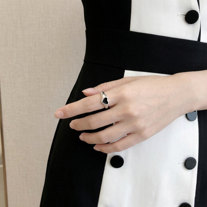 Black heart wishbone ring on hand, silver frame around black enamel heart