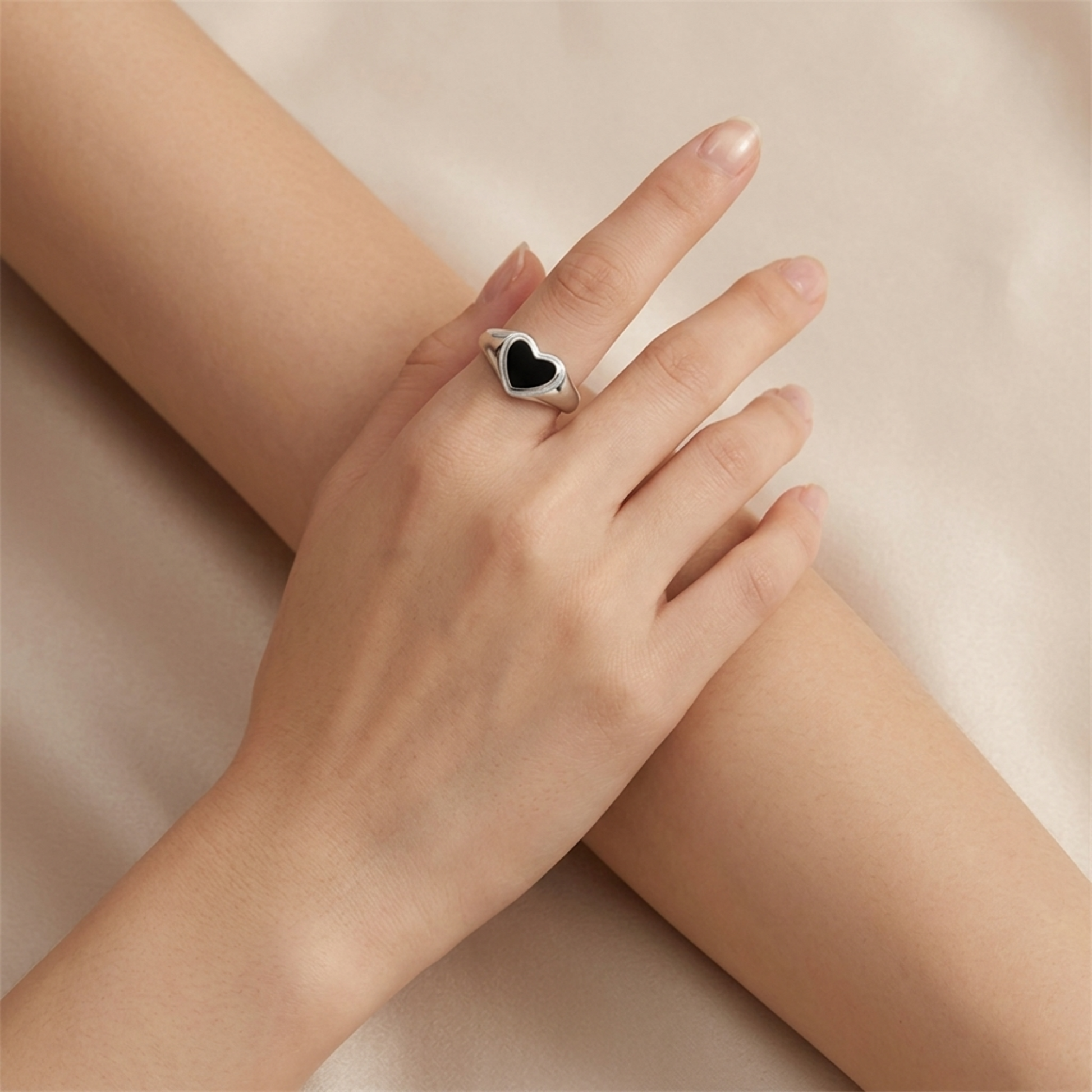Black heart ring on finger, silver-tone wishbone band with black enamel heart