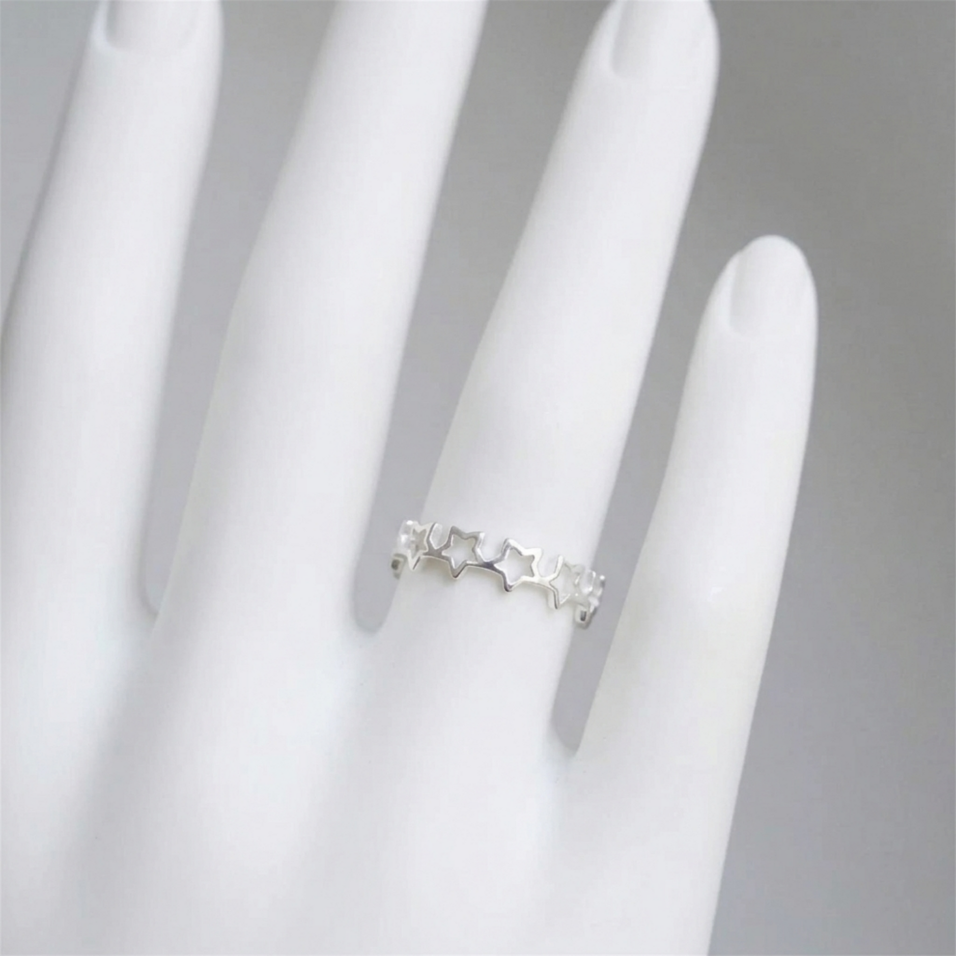 Star link ring on a hand, silver-tone band with small star charms