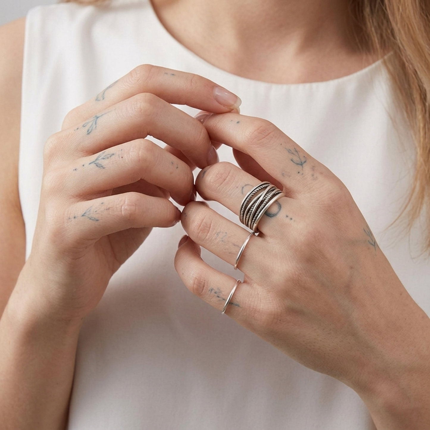 Oxidised rope crossover ring worn on fingers, stacked rope and etched bands
