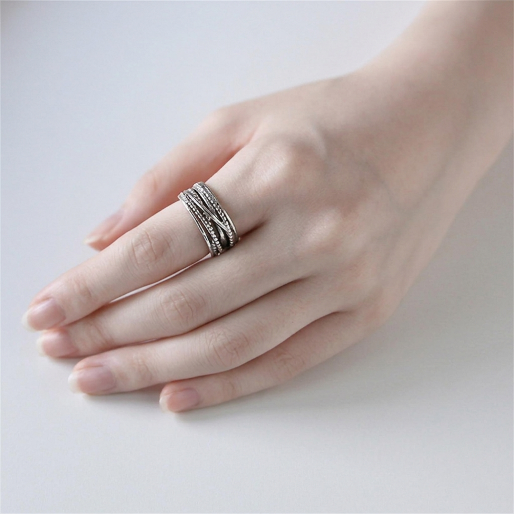 Oxidised rope crossover ring on hand, three stacked rope-style bands