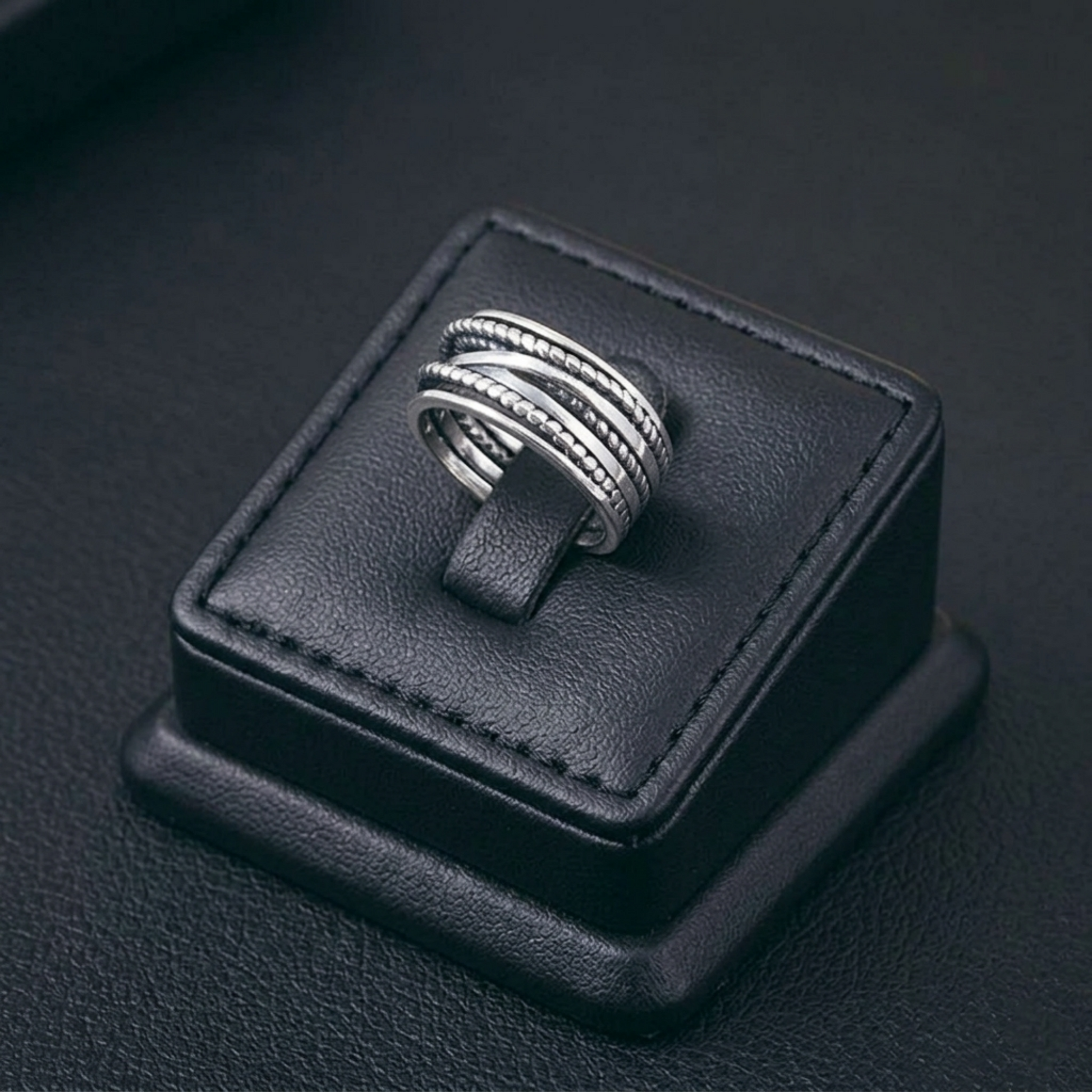 BISELTD oxidised rope crossover ring on black display cushion, stacked rope bands