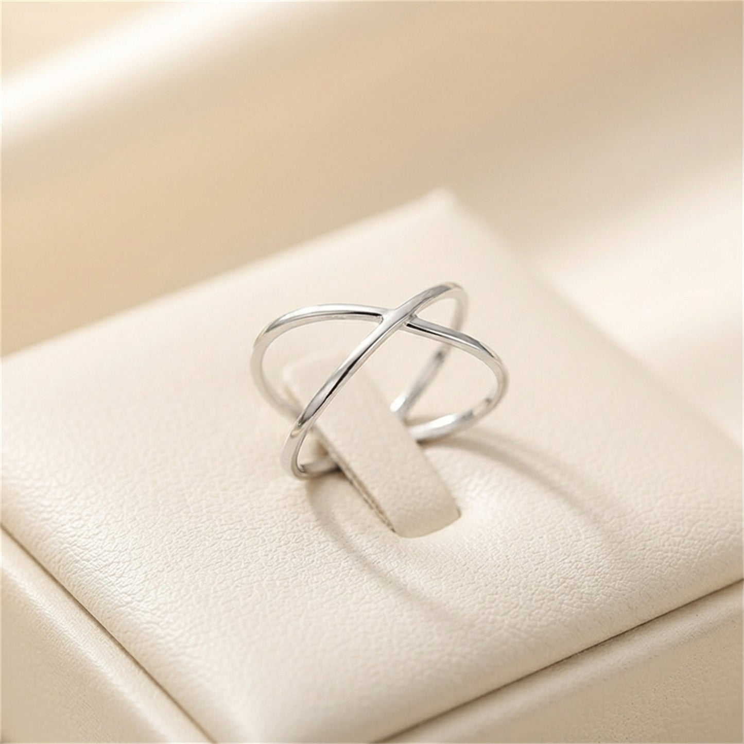 Silver criss-cross love knot ring with crossed bands, angled view.