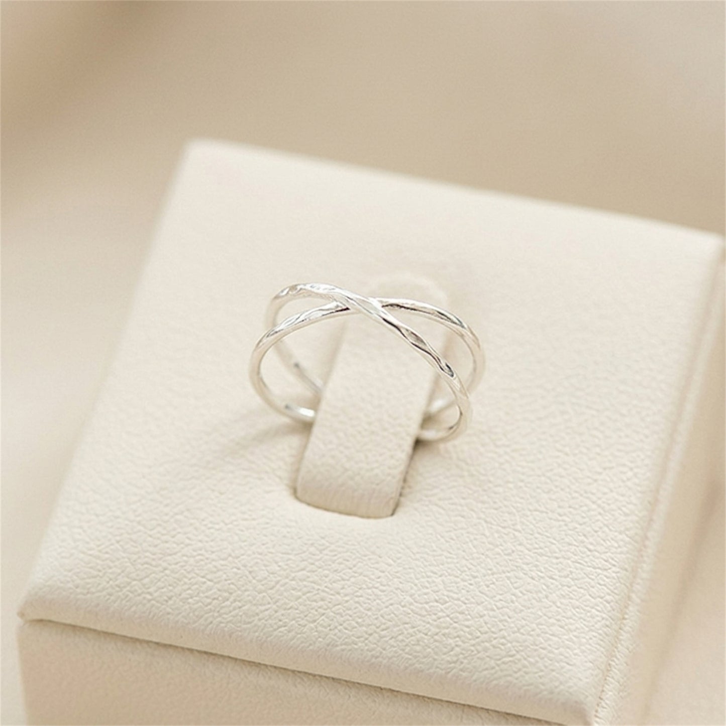 Silver criss-cross knot textured ring displayed on a white jewelry box