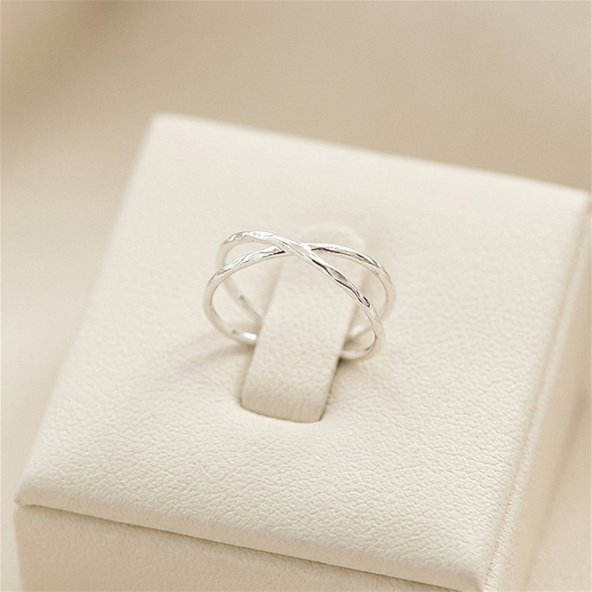 Silver criss-cross knot textured ring displayed on a white jewelry box