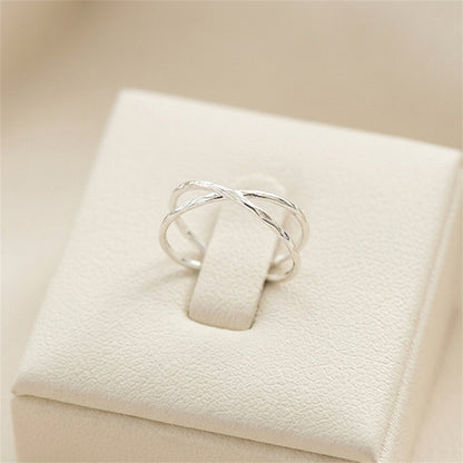 Silver criss-cross knot textured ring displayed on a white jewelry box