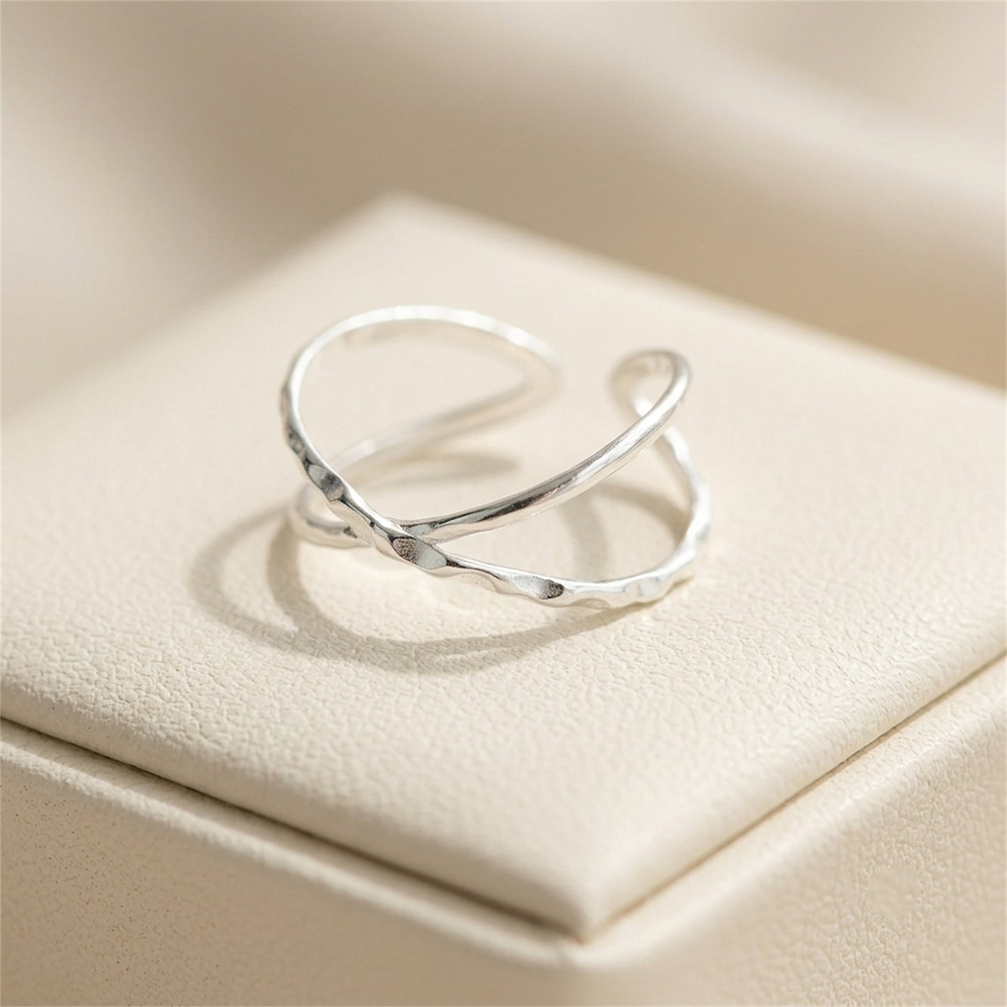 Silver criss-cross knot textured ring resting on a jewelry box