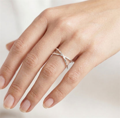Silver criss-cross knot ring on an open palm