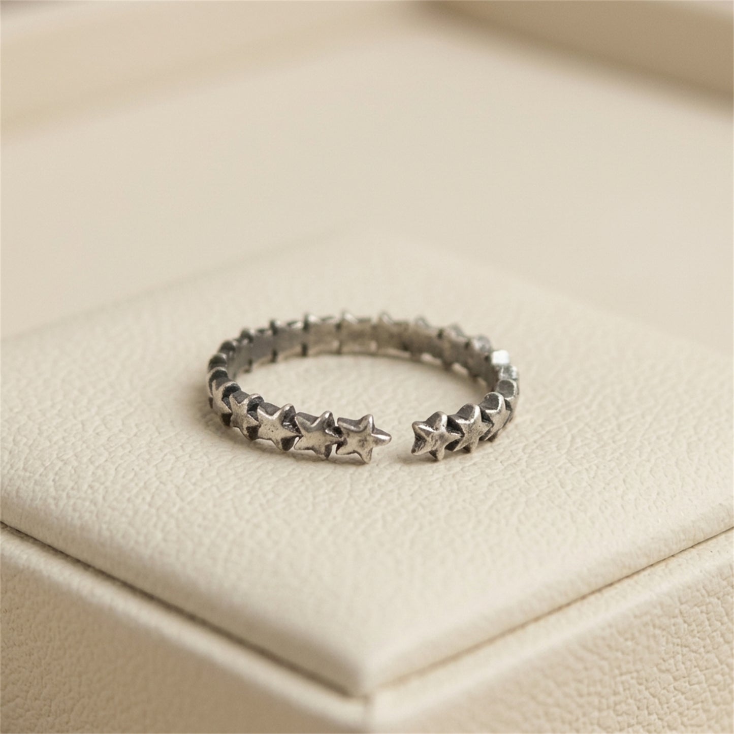 Oxidised linked stars ring on display cushion, silver-toned star-link band