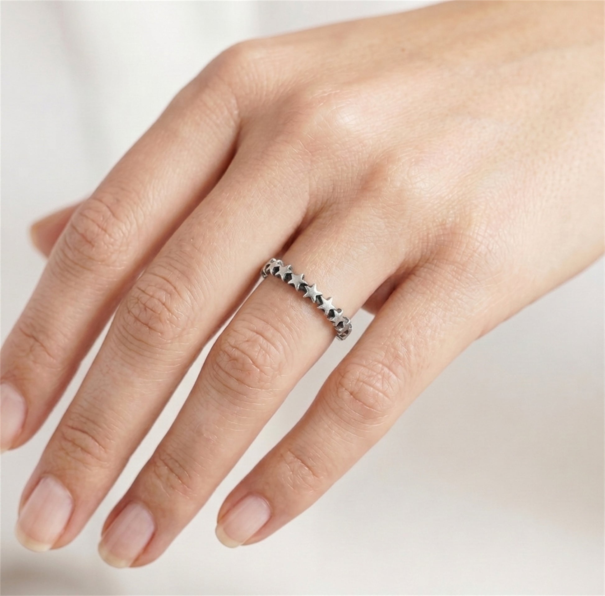 Oxidised linked stars ring on finger, silver-toned band with star motifs