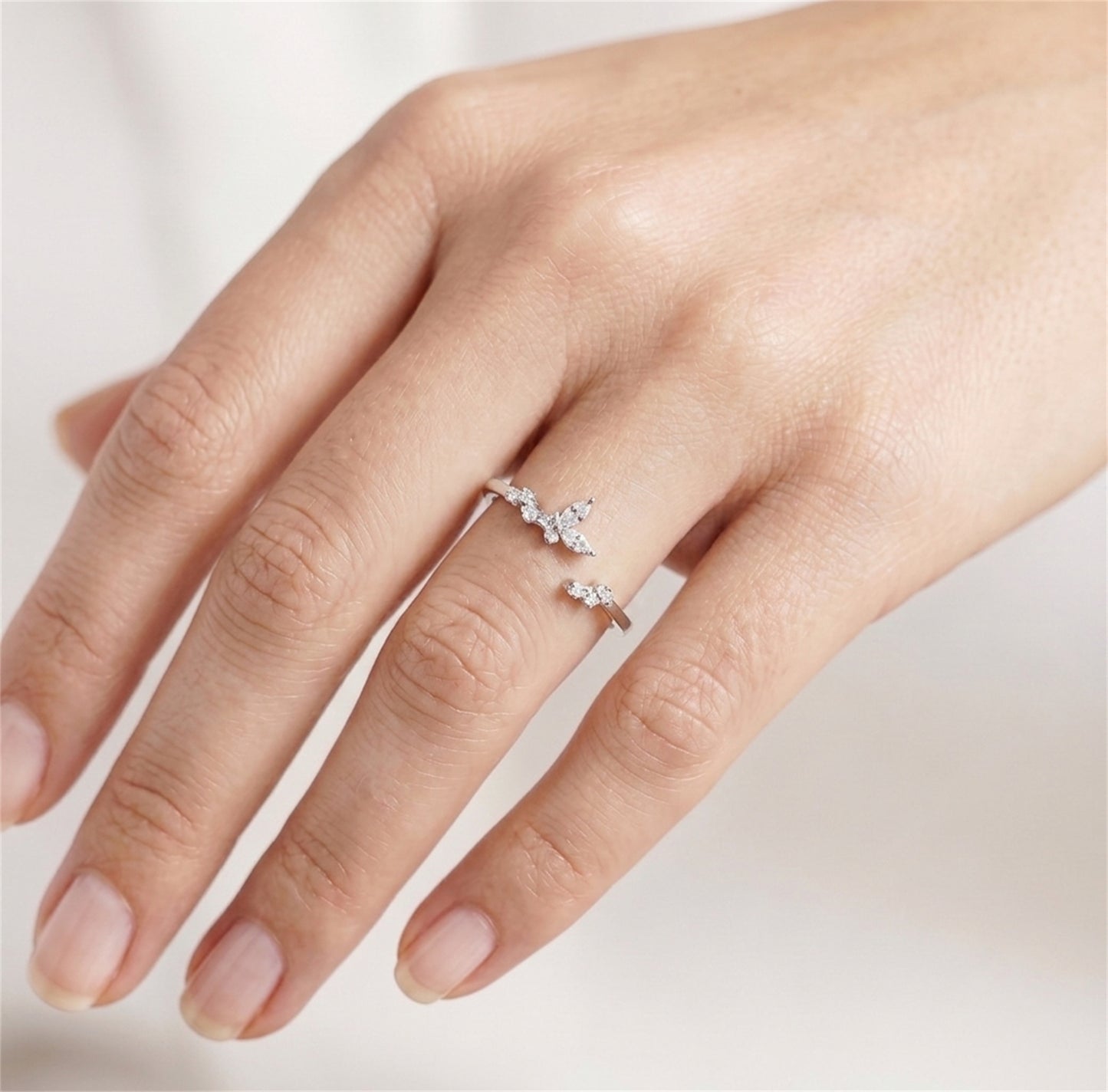 Silver CZ butterfly ring on finger with two butterfly stone accents