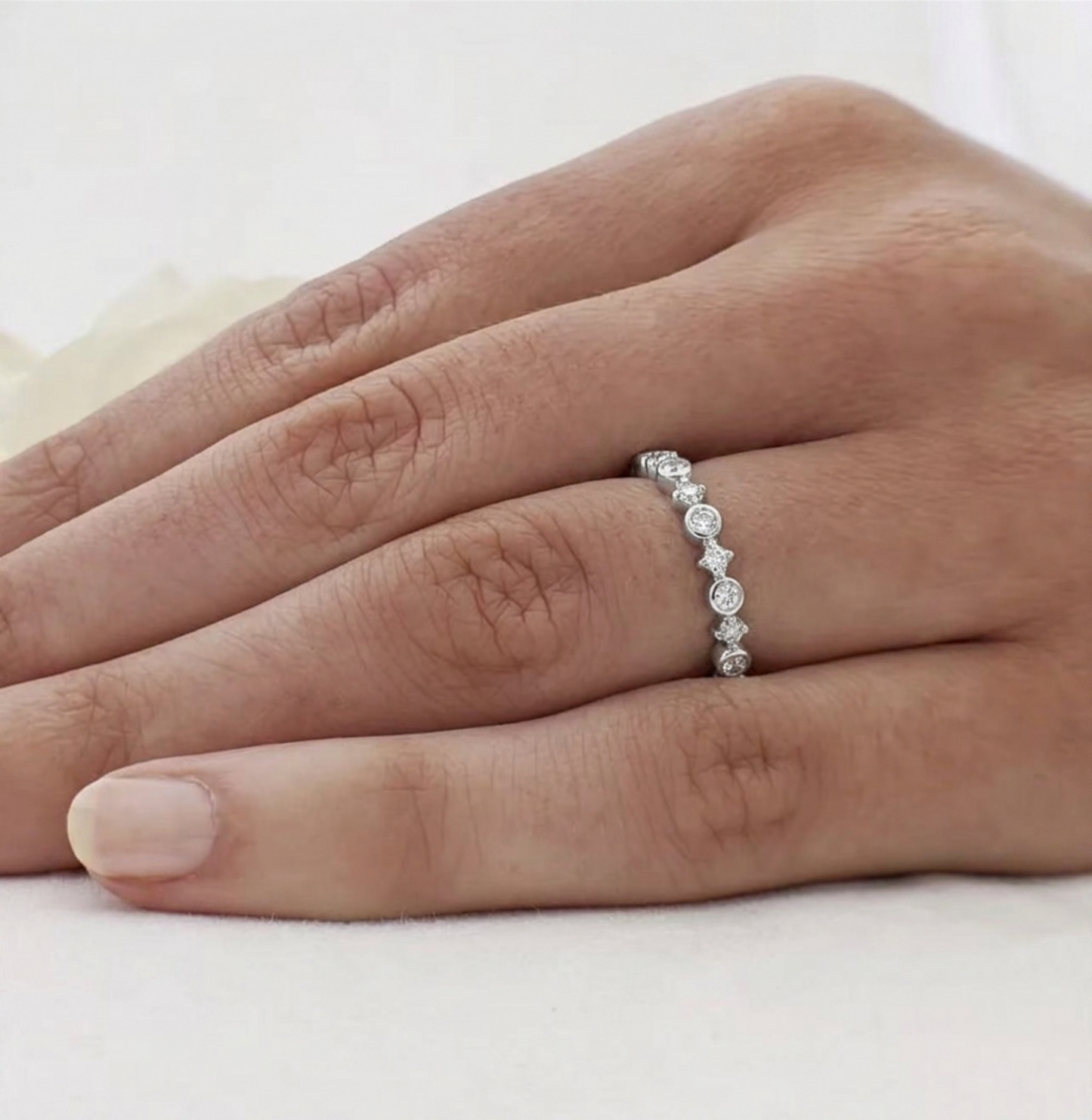 Silver CZ ring on finger with linked star bezels and round stones