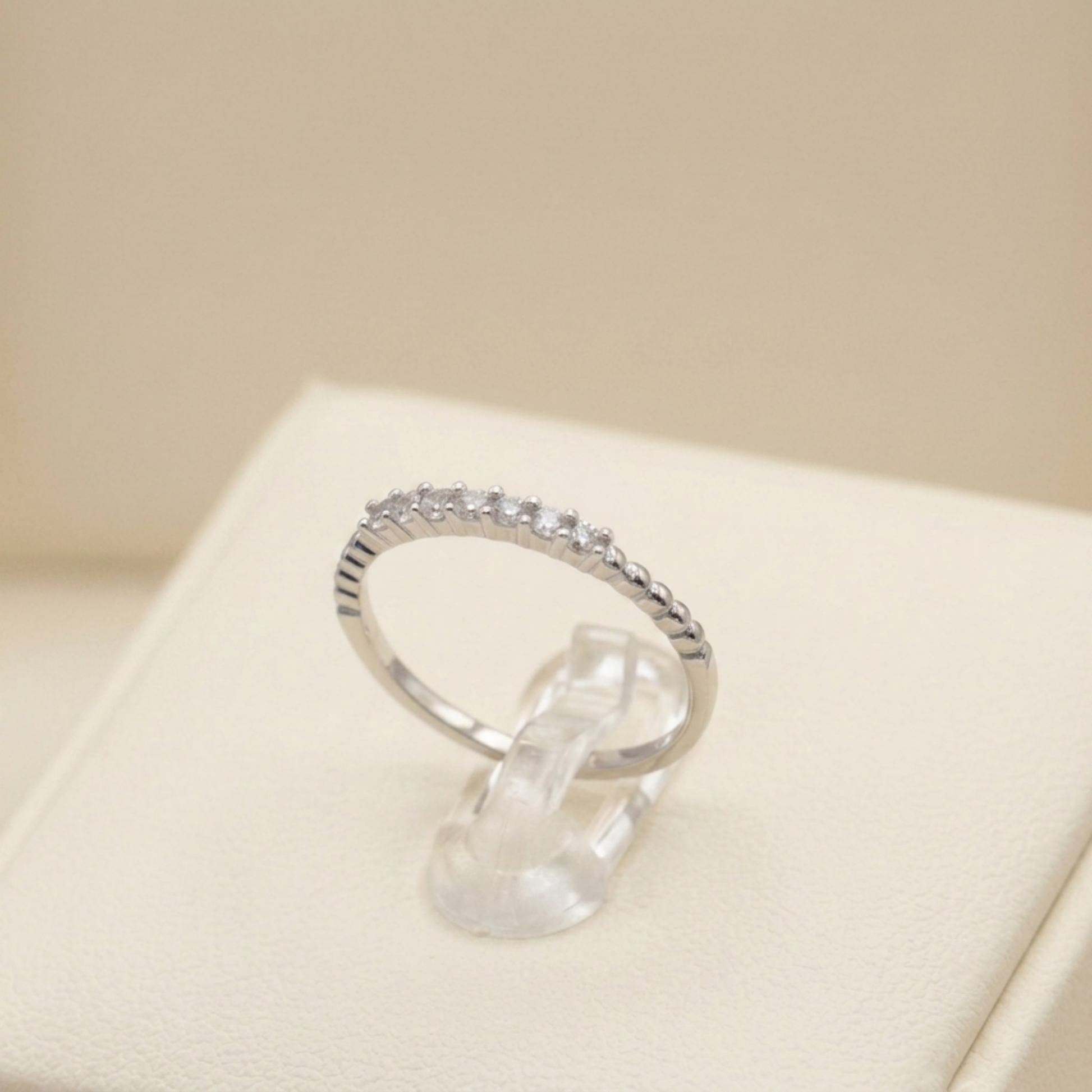 Silver half-eternity beaded ring with small clear stones in a half row.
