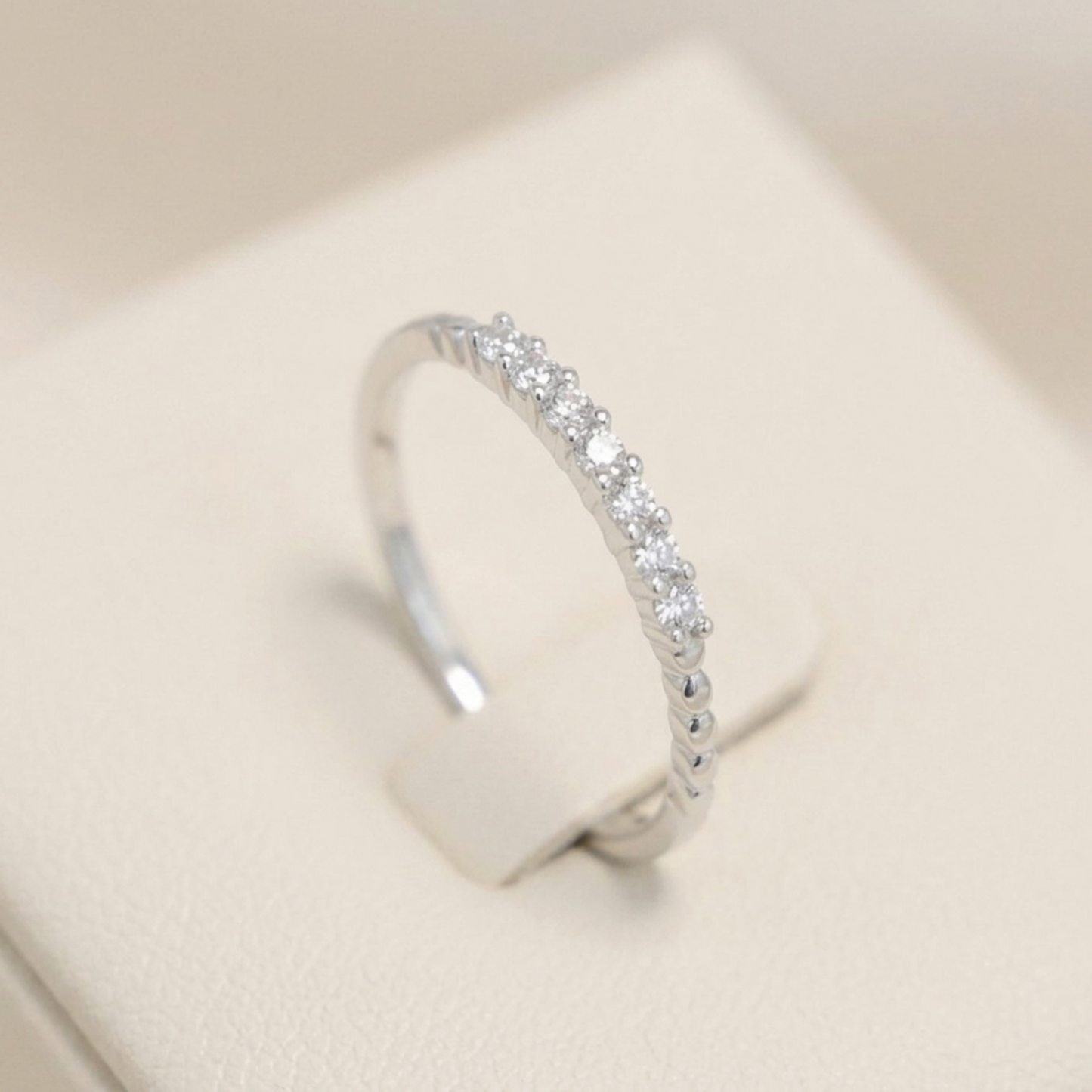 Silver half-eternity beaded ring with clear pavé stones along the top half.
