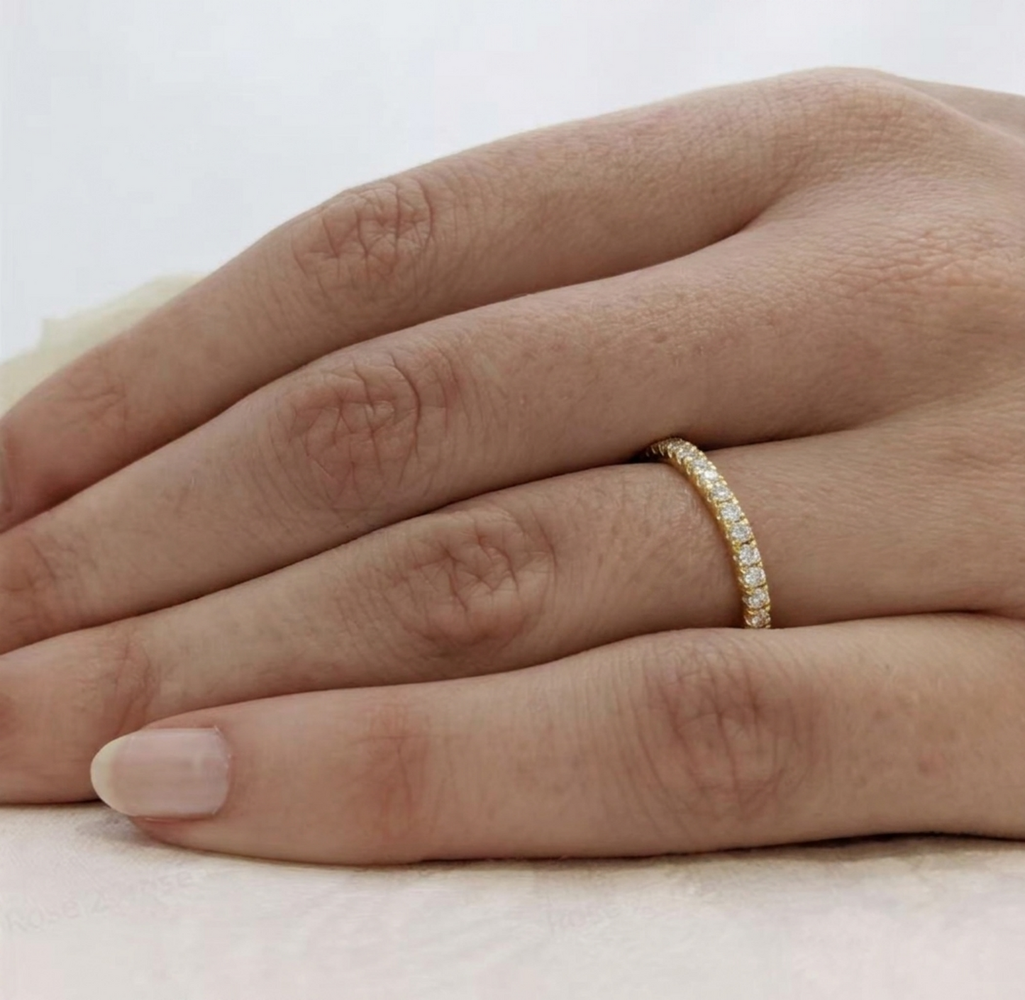 Gold CZ stacking eternity band on finger, pavé stones around the band
