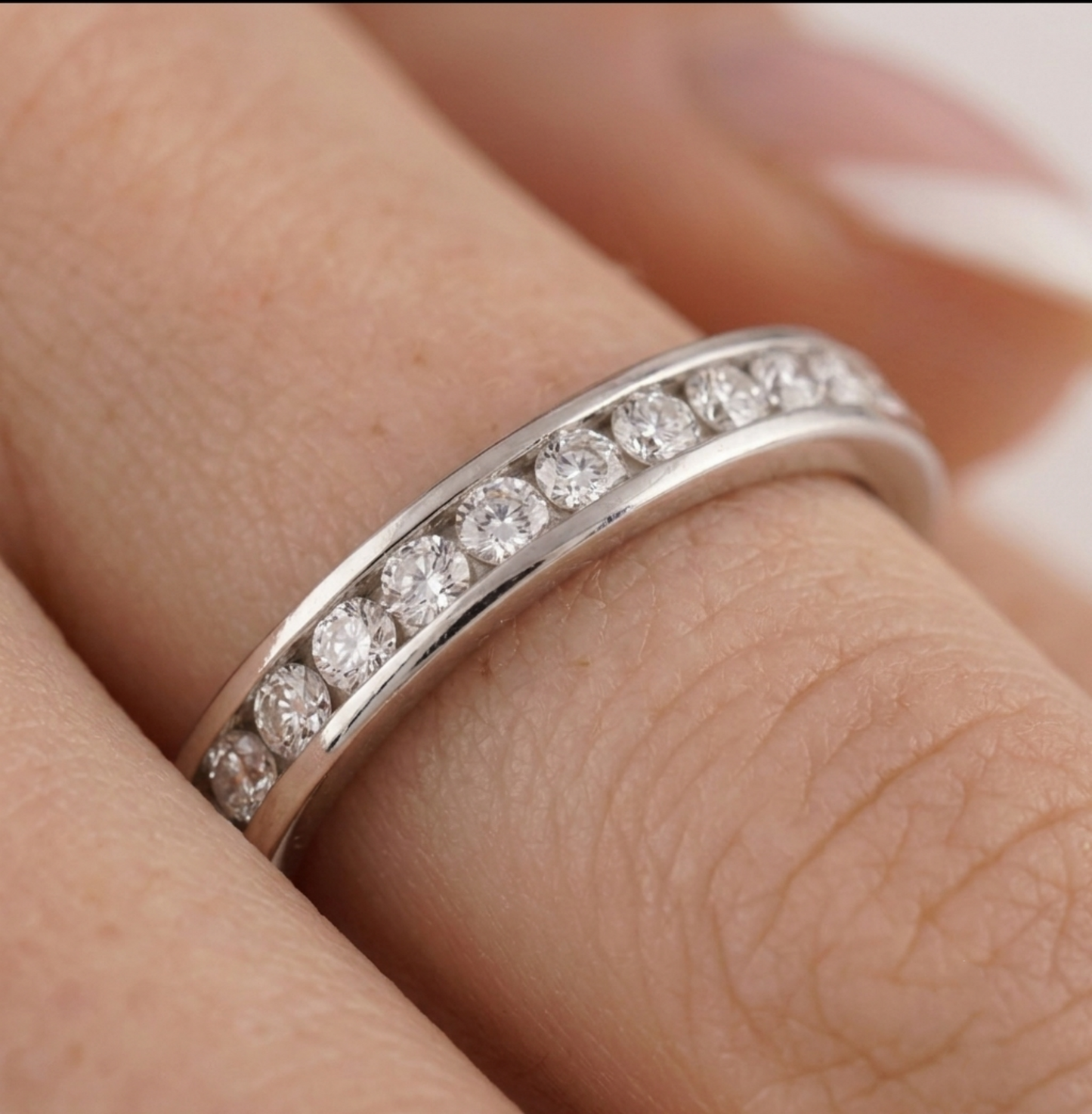 Silver channel eternity ring with round stones along the band on a finger