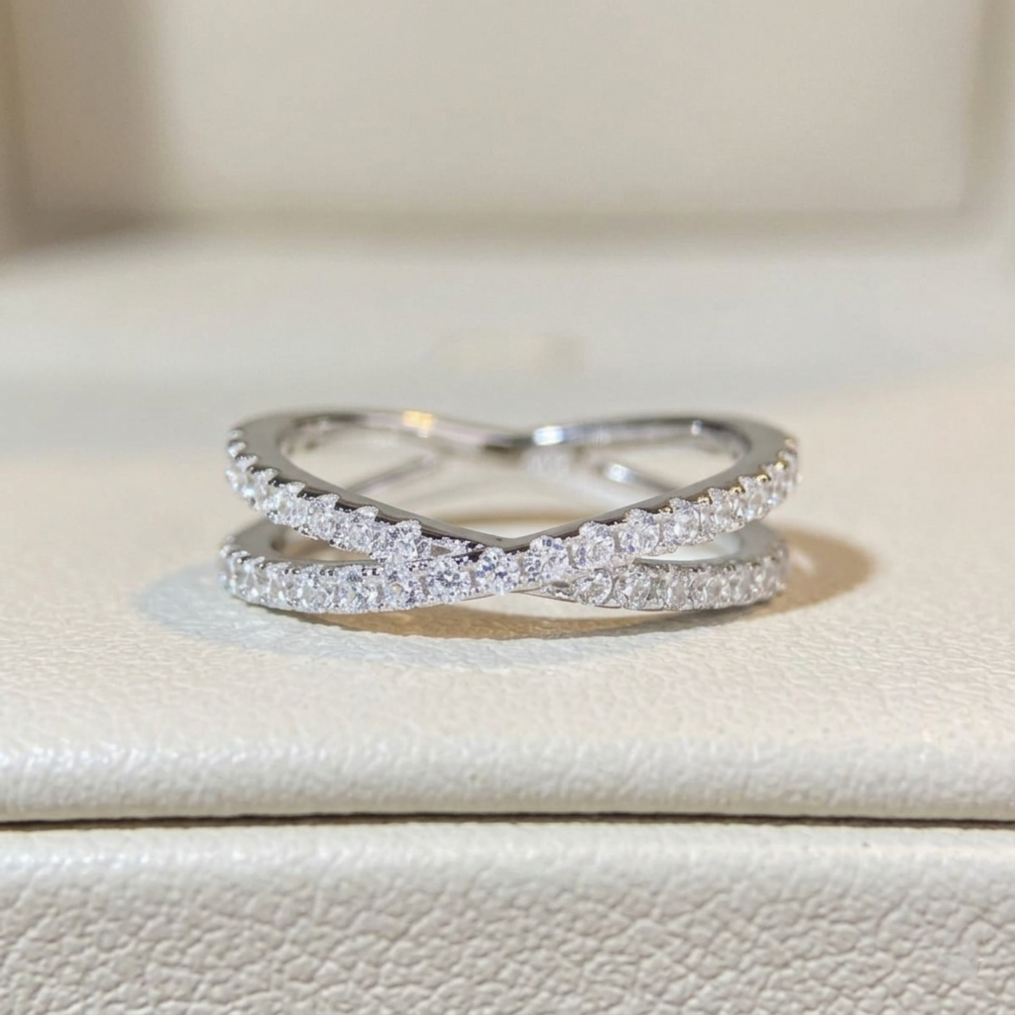 Infinity criss-cross ring on a display, two silver bands with pavé sparkle