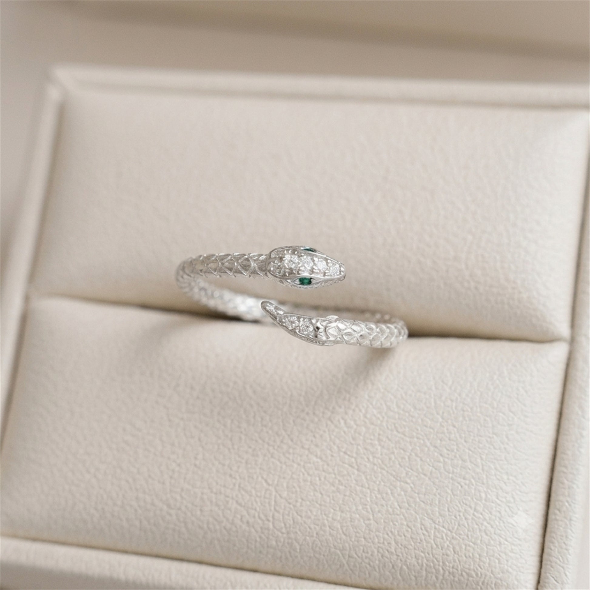 Silver-tone snake wrap ring with green eye and clear stone accents