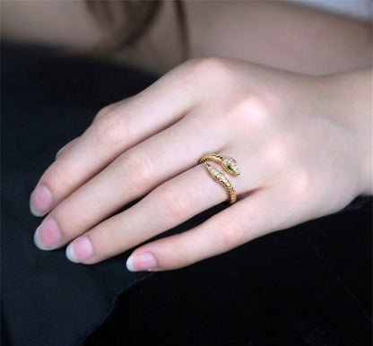 Gold-tone snake wrap ring on hand with green eye and clear stones