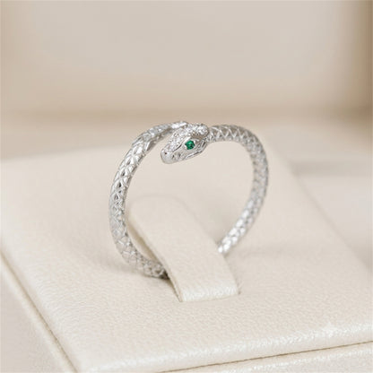 Silver-tone snake wrap ring with green eye and clear stone details